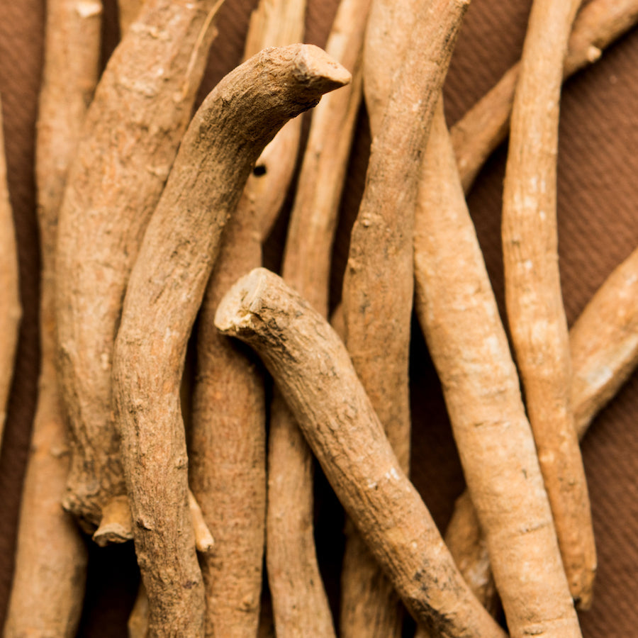 Close-up of dried ashwagandha roots showcasing their rough, twisted texture against a dark brown background