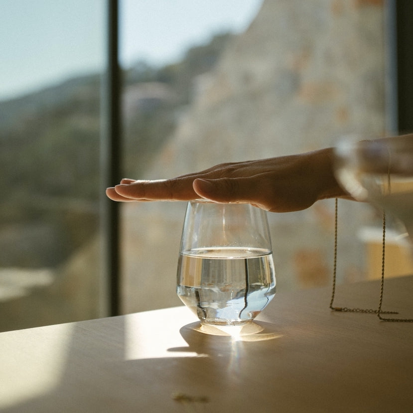 Hand hovering above a glass of water.