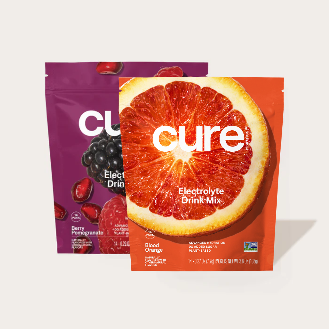 Two Cure Electrolyte Drink Mix packets, one Blood Orange flavor and one Berry Pomegranate flavor, showing the brand name and flavor names.