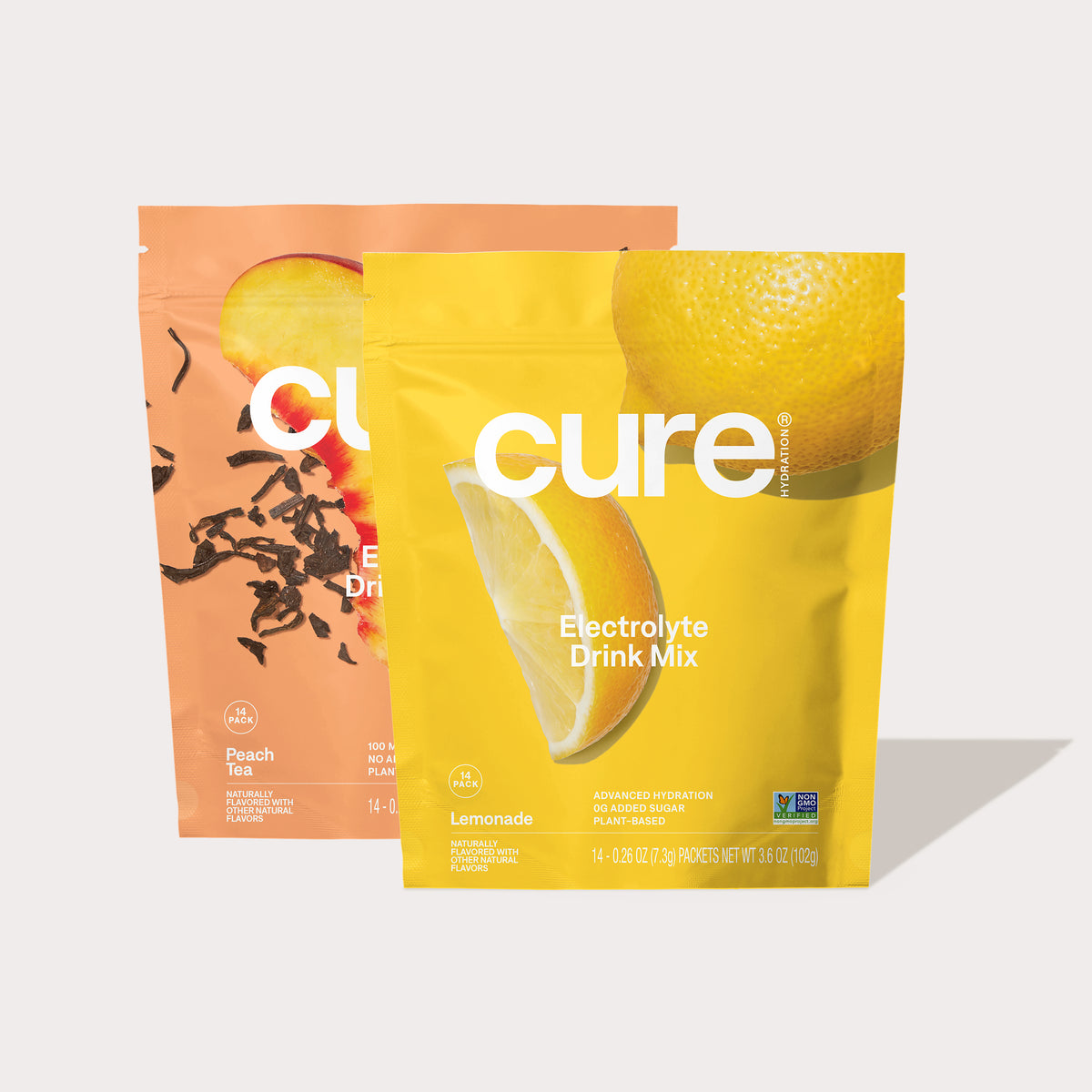 Two Cure electrolyte drink mix packets: one Lemonade flavor in a yellow package and one Peach Tea flavor in a peach-colored package.
