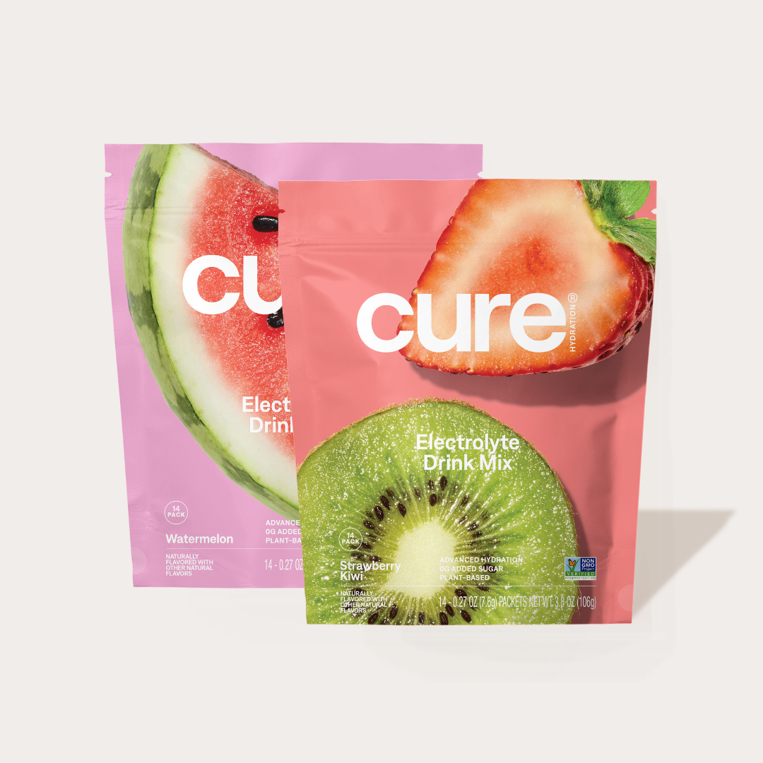 Two pink packets of Cure Electrolyte Drink Mix, one Watermelon flavor with a watermelon image, and one Strawberry Kiwi flavor with a kiwi and strawberry image.