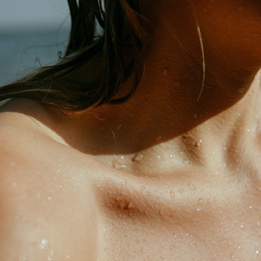 Close-up of a person's wet shoulder and neck with water droplets on skin, illustrating hydration.
