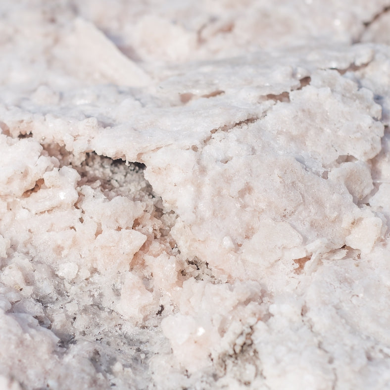 Close-up of coarse, crystalline salt deposits with a rough texture, likely unrefined salt crystals.