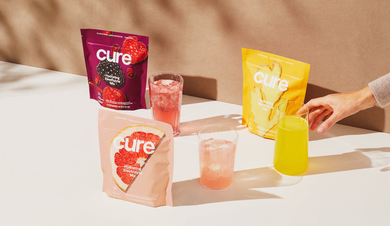 Hand reaching for a 'Cure' ginger electrolyte drink among various flavors.