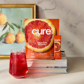 Front view of Blood Orange electrolyte drink mix pouch and stick with large orange image and glass of red drink