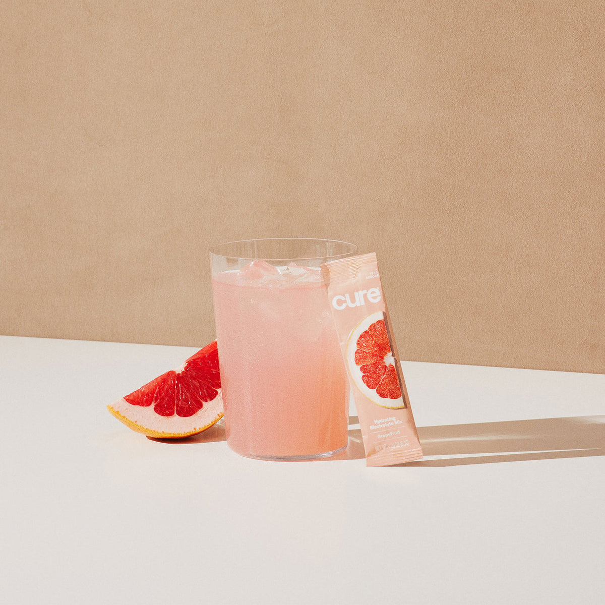 Pink grapefruit drink with mix packet and citrus fruit.