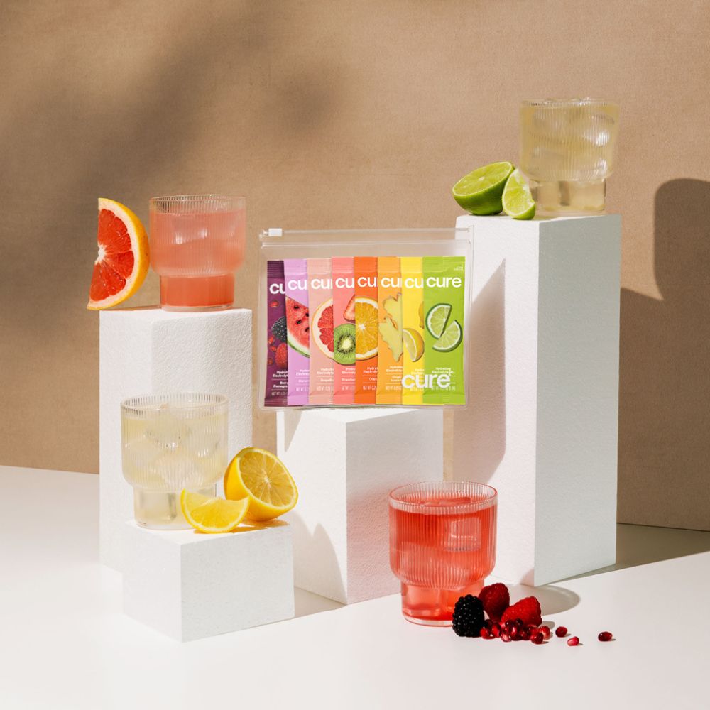 Hydration mix packets display with citrus fruits and glasses on pedestals.